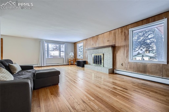 living room featuring a brick fireplace, light hardwood / wood-style flooring, wood walls, and baseboard heating