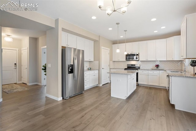 kitchen with sink, appliances with stainless steel finishes, white cabinetry, a kitchen island, and decorative light fixtures