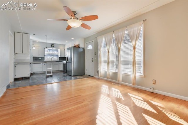 unfurnished living room with sink, wood-type flooring, and ceiling fan