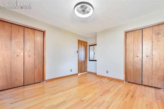 unfurnished bedroom with multiple closets and light wood-type flooring