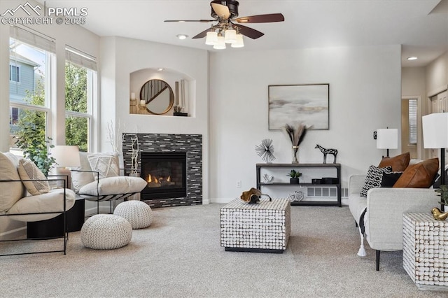 carpeted living room featuring ceiling fan and a fireplace