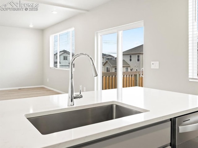 interior details with a sink, baseboards, and light countertops
