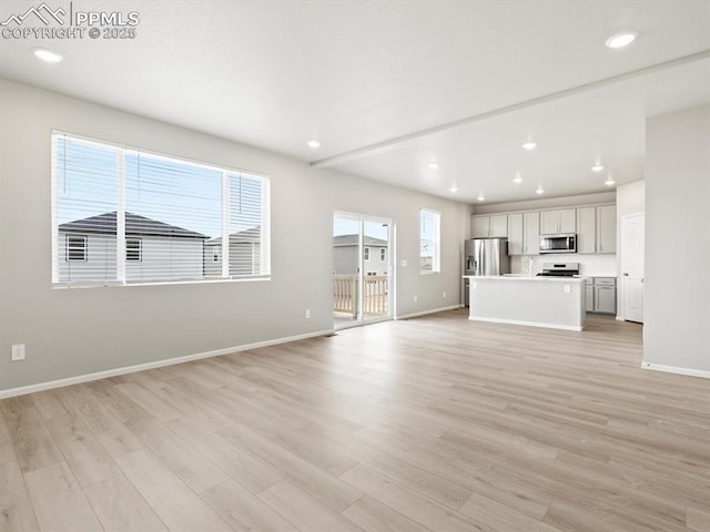 unfurnished living room featuring recessed lighting, baseboards, and light wood finished floors