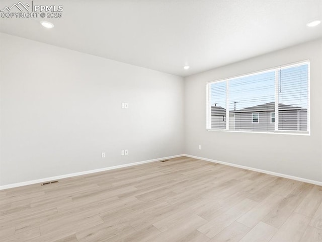 unfurnished room featuring light wood finished floors, visible vents, and baseboards