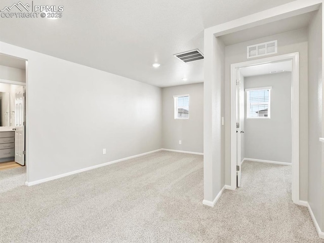 carpeted empty room featuring visible vents and baseboards