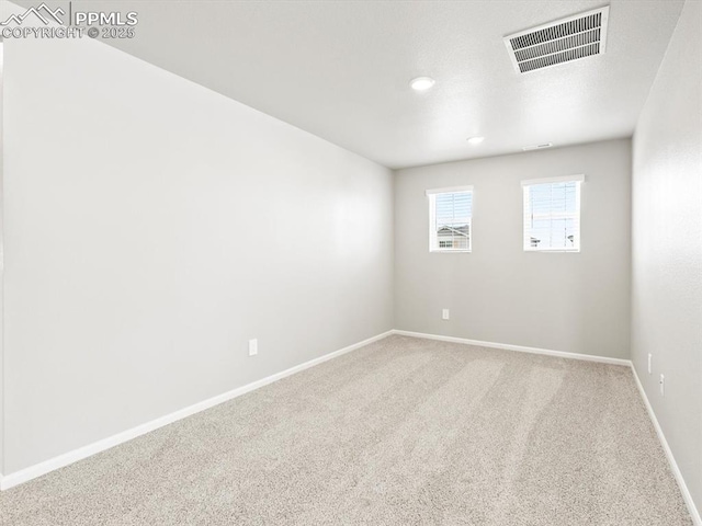 carpeted spare room with visible vents and baseboards