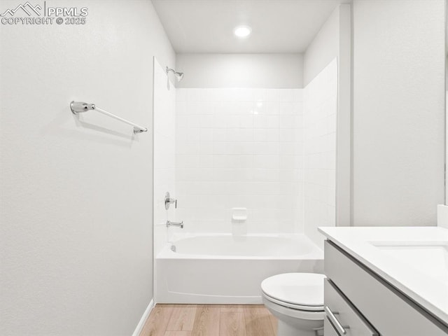 bathroom with vanity, wood finished floors, baseboards, tub / shower combination, and toilet