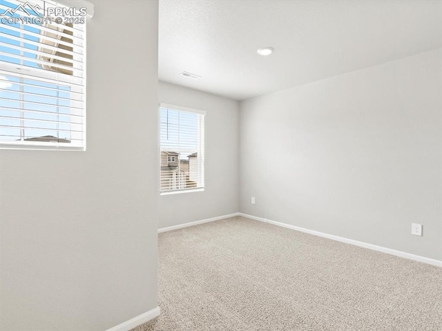 spare room with visible vents, baseboards, and carpet flooring