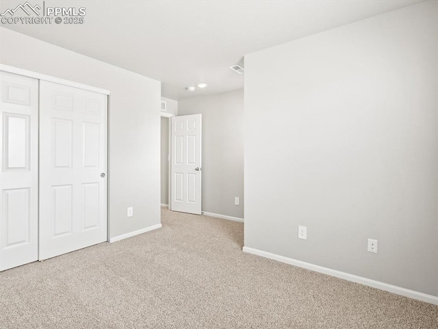unfurnished bedroom with a closet, baseboards, carpet, and visible vents