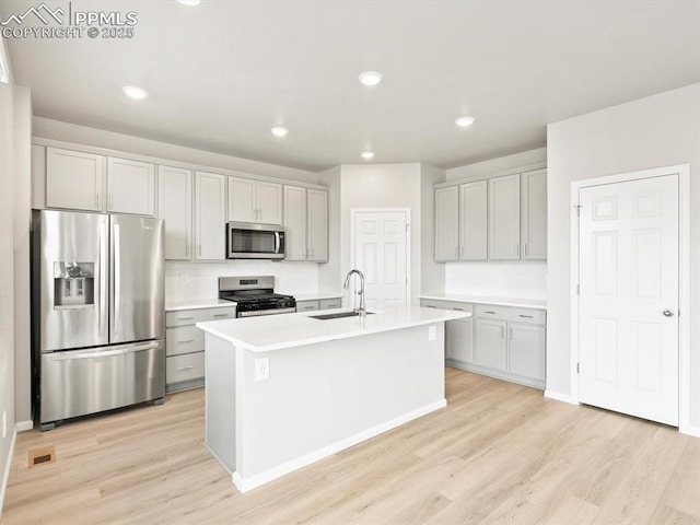 kitchen featuring a sink, stainless steel appliances, light wood-type flooring, and light countertops