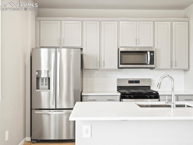 kitchen featuring decorative backsplash, light countertops, appliances with stainless steel finishes, and a sink