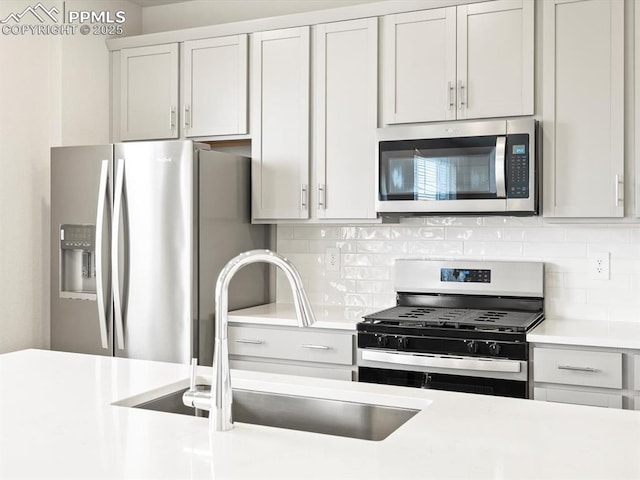 kitchen with a sink, stainless steel appliances, tasteful backsplash, and light countertops