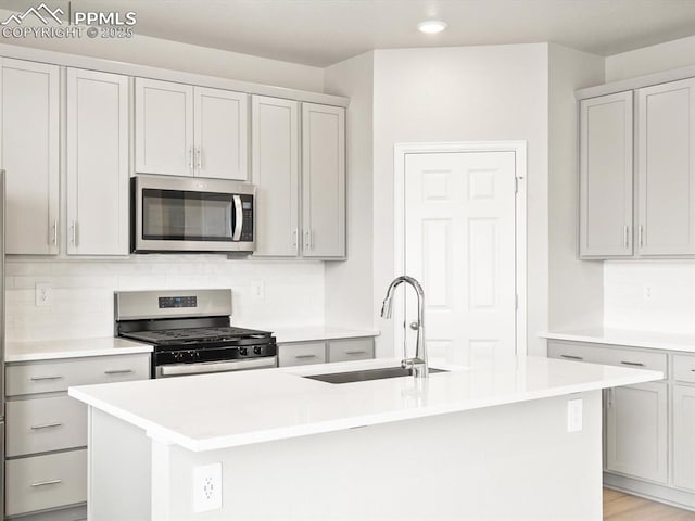 kitchen with a sink, tasteful backsplash, appliances with stainless steel finishes, and light countertops
