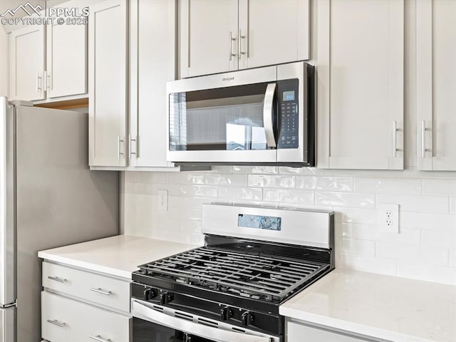kitchen with backsplash, white cabinetry, and stainless steel appliances
