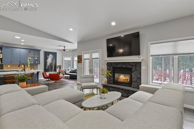 living room with lofted ceiling, a fireplace, recessed lighting, and wood finished floors