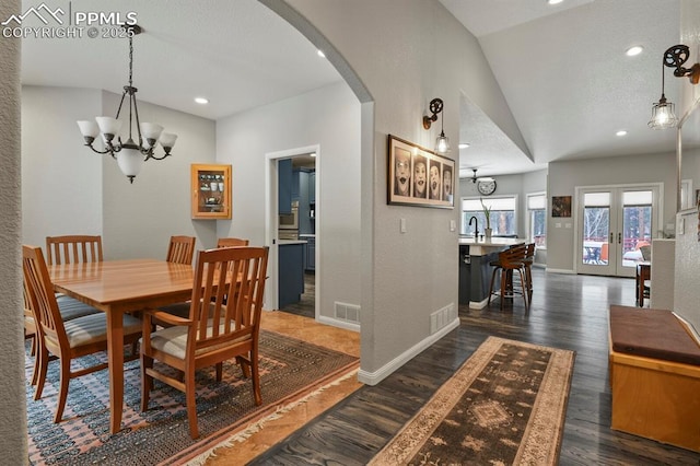 dining room with arched walkways, visible vents, french doors, dark wood finished floors, and an inviting chandelier