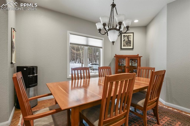 dining space featuring baseboards, a notable chandelier, and a textured wall