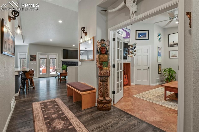 foyer entrance with french doors, a fireplace, baseboards, and wood finished floors