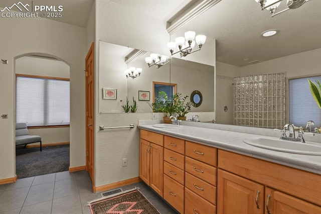 bathroom with double vanity, tile patterned flooring, baseboards, and a sink