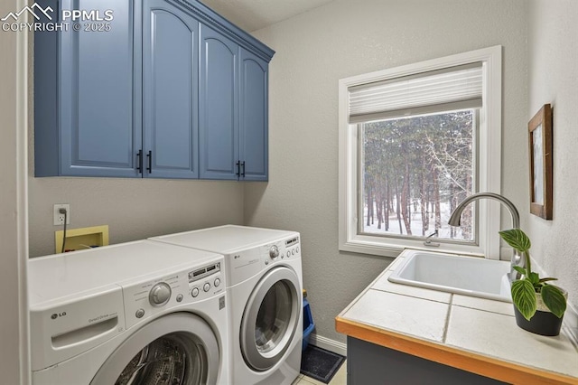 laundry area featuring cabinet space, separate washer and dryer, a sink, and a textured wall