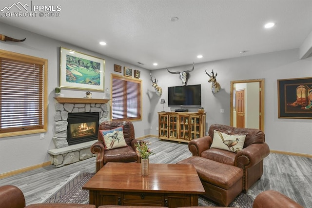 living area featuring recessed lighting, a fireplace, baseboards, and wood finished floors