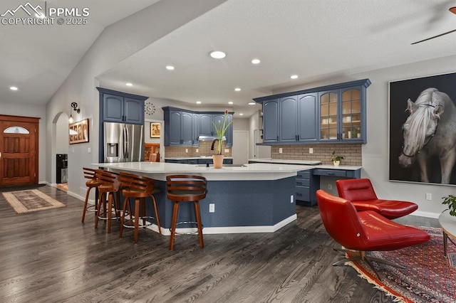 kitchen featuring light countertops, blue cabinetry, dark wood-type flooring, and stainless steel refrigerator with ice dispenser