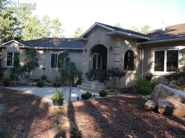 view of front of property featuring a shingled roof and stucco siding