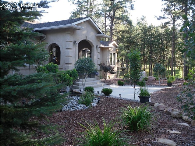 view of front of home featuring a shingled roof and stucco siding