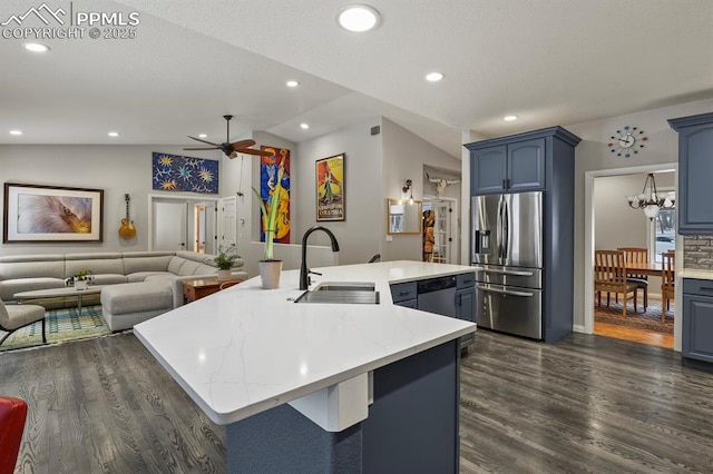 kitchen featuring an island with sink, appliances with stainless steel finishes, open floor plan, blue cabinets, and a sink