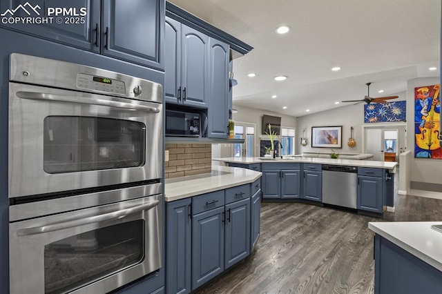 kitchen featuring lofted ceiling, dark wood-style flooring, a sink, blue cabinetry, and appliances with stainless steel finishes