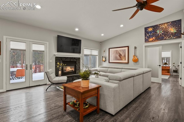 living room featuring vaulted ceiling, a stone fireplace, french doors, and dark wood-style flooring