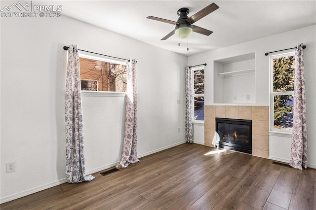 unfurnished living room featuring a tile fireplace, wood-type flooring, and ceiling fan