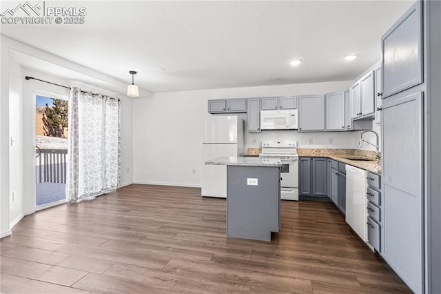 kitchen featuring sink, gray cabinetry, hanging light fixtures, a kitchen island, and white appliances