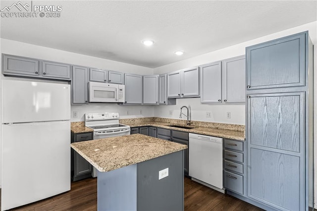 kitchen with dark hardwood / wood-style flooring, sink, white appliances, and a kitchen island