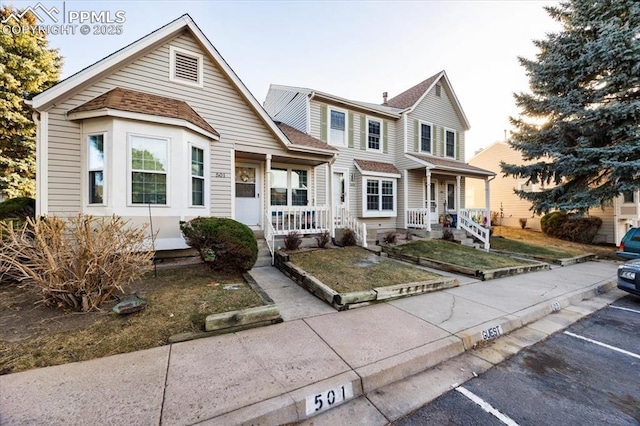 view of front of home featuring covered porch, a shingled roof, uncovered parking, and a front lawn