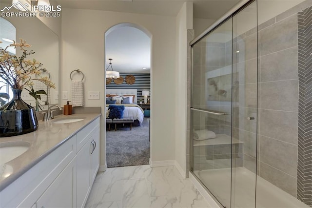 ensuite bathroom featuring a sink, marble finish floor, a shower stall, double vanity, and ensuite bath