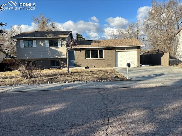 split level home with a garage, concrete driveway, and fence