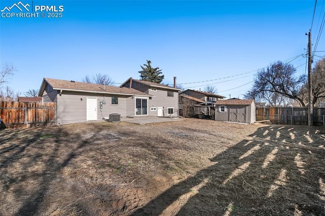 rear view of property with an outbuilding, a patio, a storage unit, cooling unit, and a fenced backyard