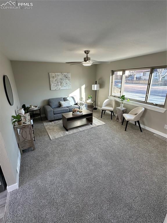 living area with carpet flooring, ceiling fan, and baseboards