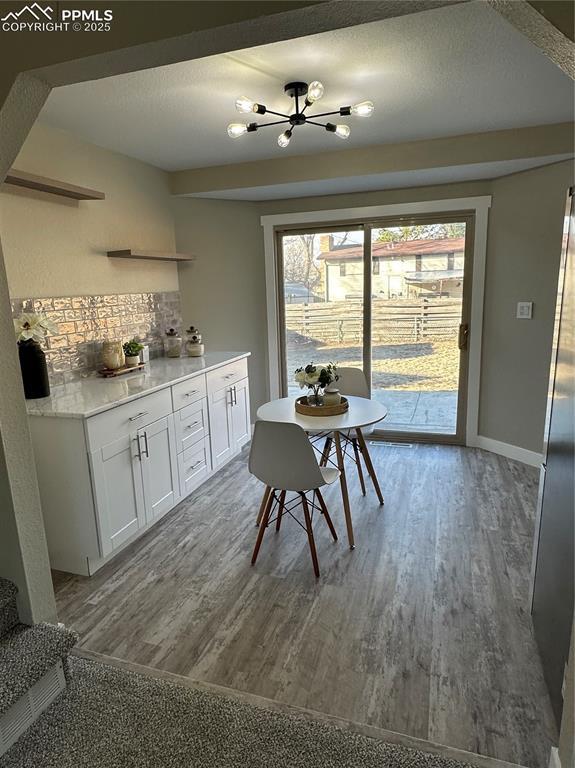 dining area with a textured ceiling, baseboards, and wood finished floors