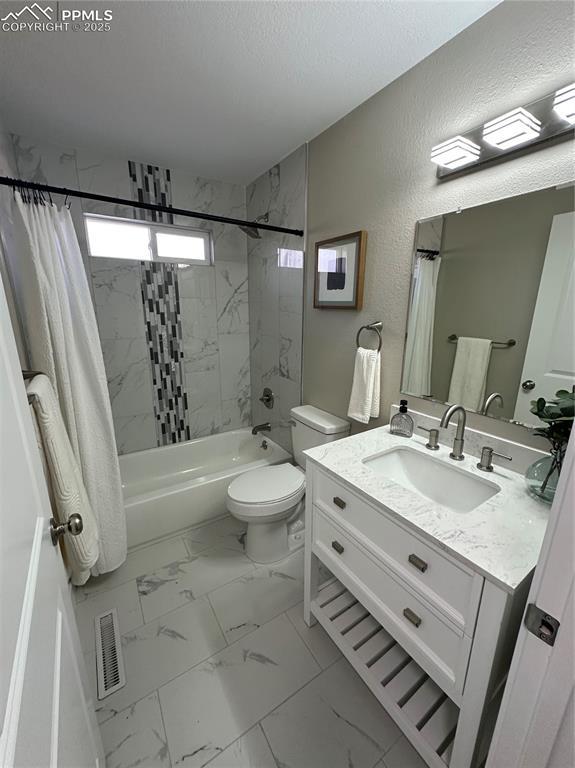 bathroom with visible vents, a textured wall, marble finish floor, a textured ceiling, and shower / bath combination with curtain