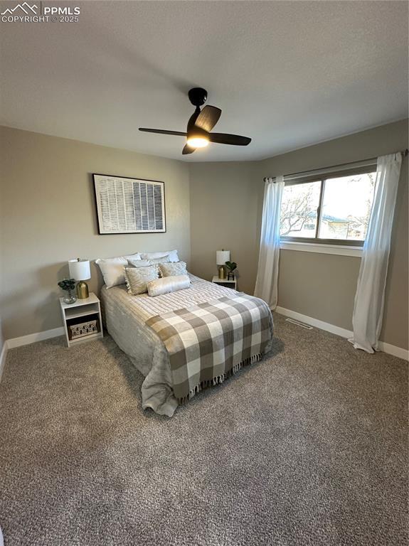 carpeted bedroom featuring a ceiling fan, visible vents, a textured ceiling, and baseboards