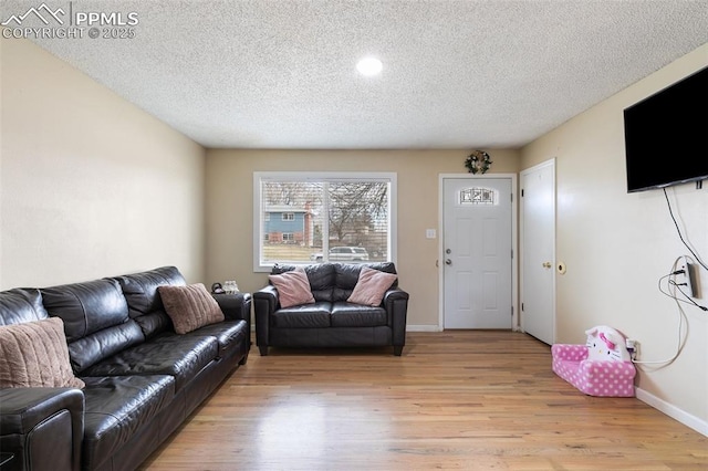 living area with baseboards, a textured ceiling, and light wood-style floors