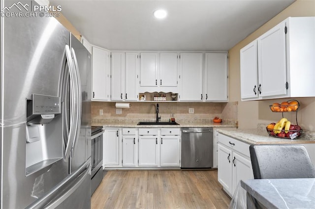 kitchen with white cabinets, a sink, light wood-type flooring, and appliances with stainless steel finishes