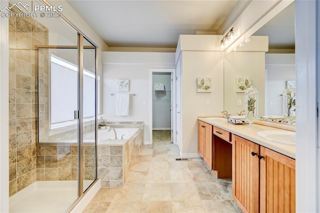 full bathroom featuring double vanity, a sink, a shower stall, and a bath