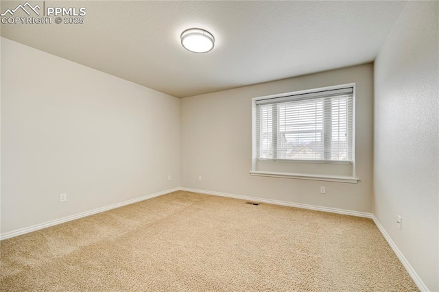 empty room featuring baseboards, visible vents, and light colored carpet