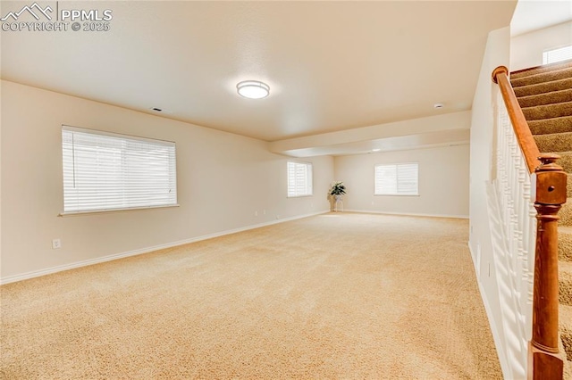 carpeted spare room featuring baseboards and stairway