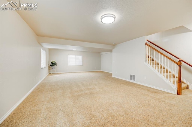 empty room with baseboards, visible vents, stairway, and carpet flooring