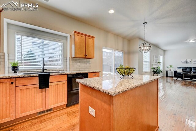 kitchen featuring light wood finished floors, visible vents, dishwasher, a kitchen island, and a sink