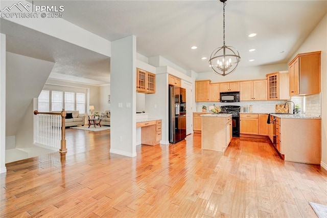 kitchen featuring black appliances, a kitchen island, open floor plan, and light wood finished floors